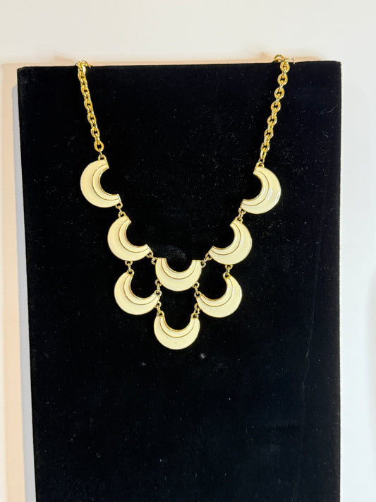 A gold signed Florenza statement necklace featuring multiple crescent moon-shaped links in cream enamel.
