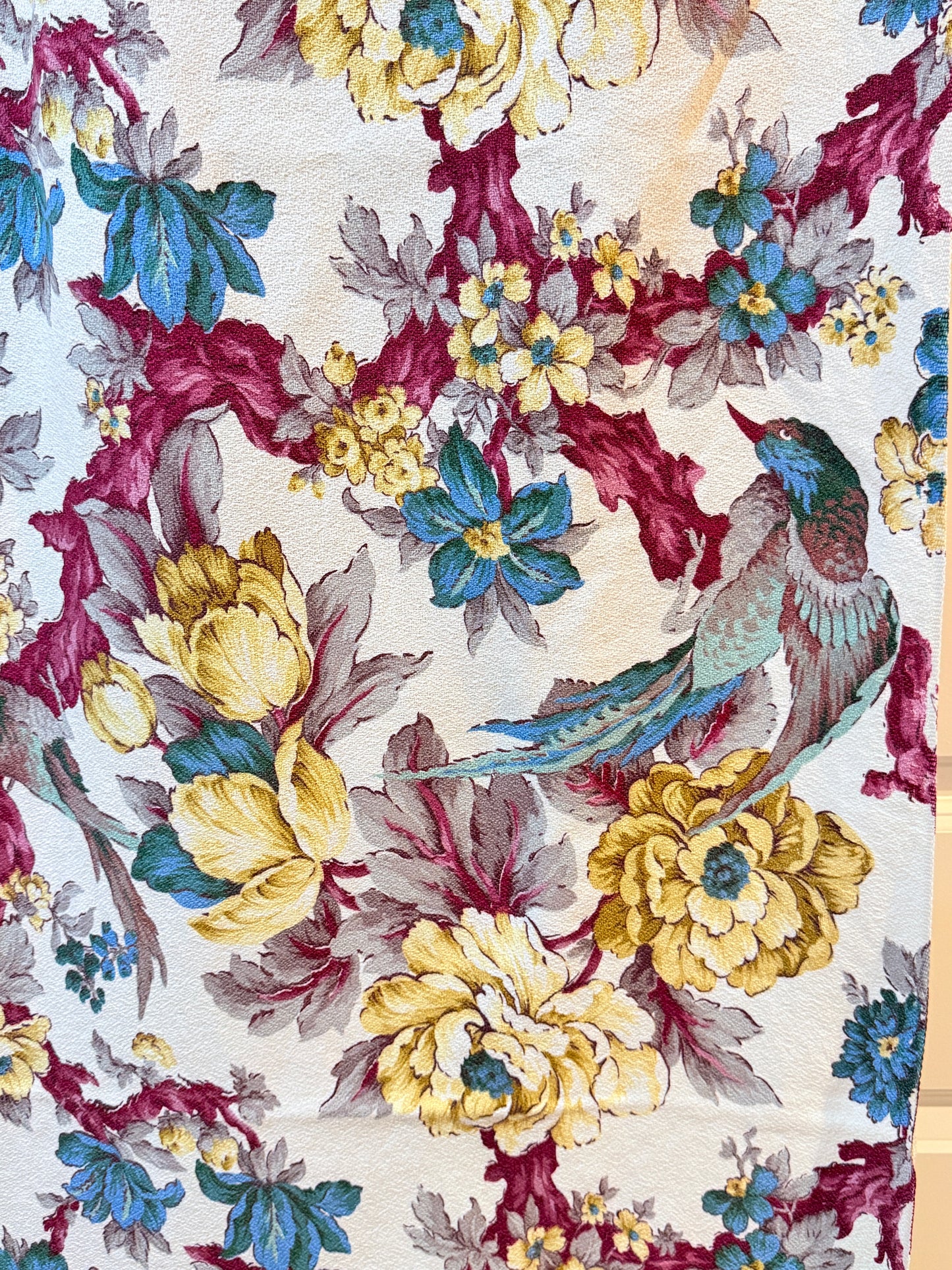 Floral and bird pattern on barkcloth vintage fabric with yellow, blue, and red colors.