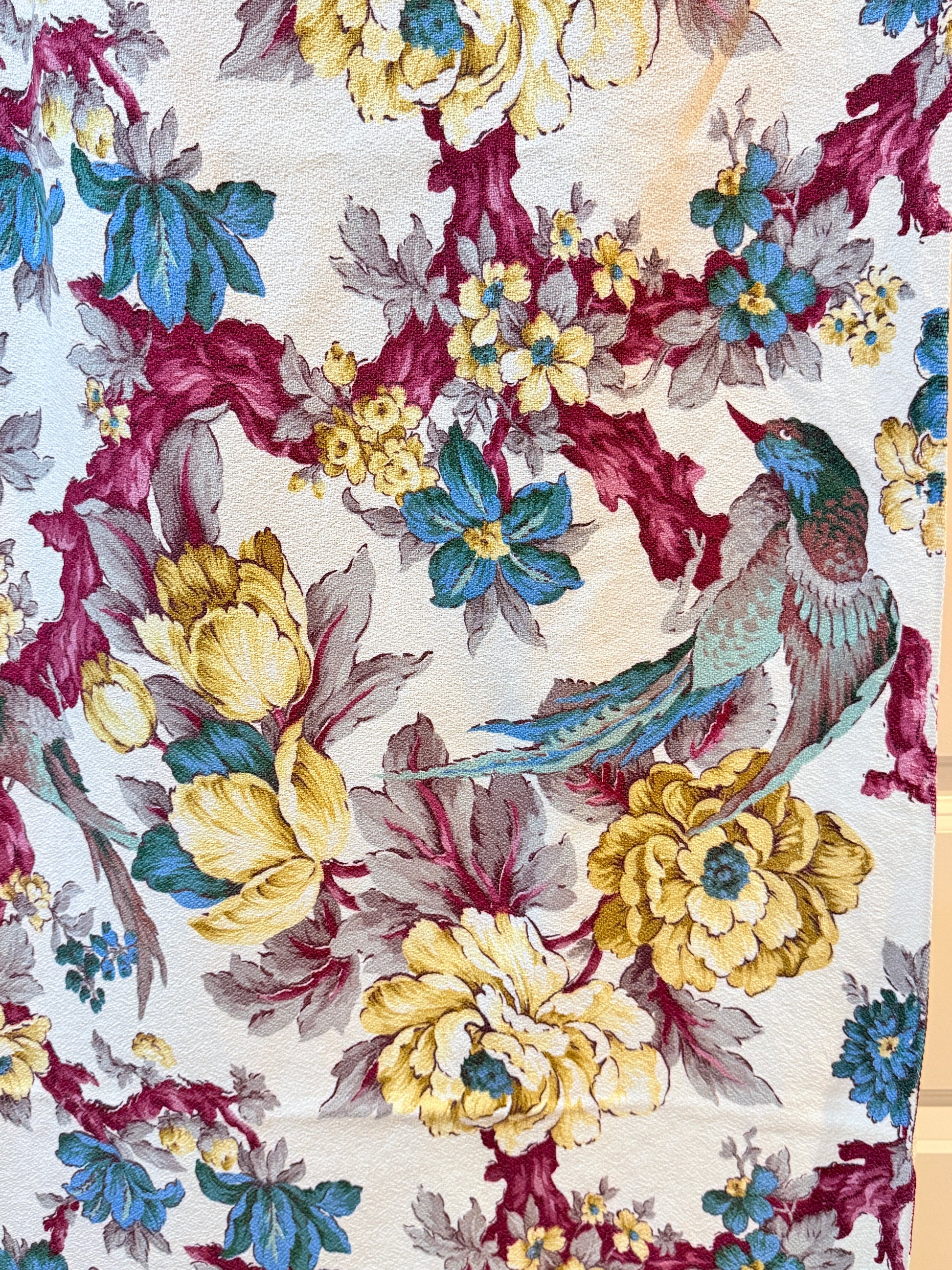 Floral and bird pattern on barkcloth vintage fabric with yellow, blue, and red colors.