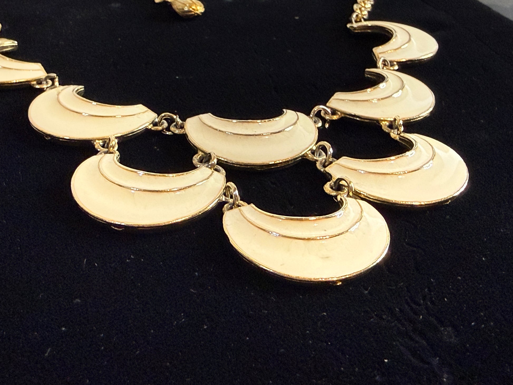 A gold signed Florenza statement necklace featuring multiple crescent moon-shaped links in cream enamel. 