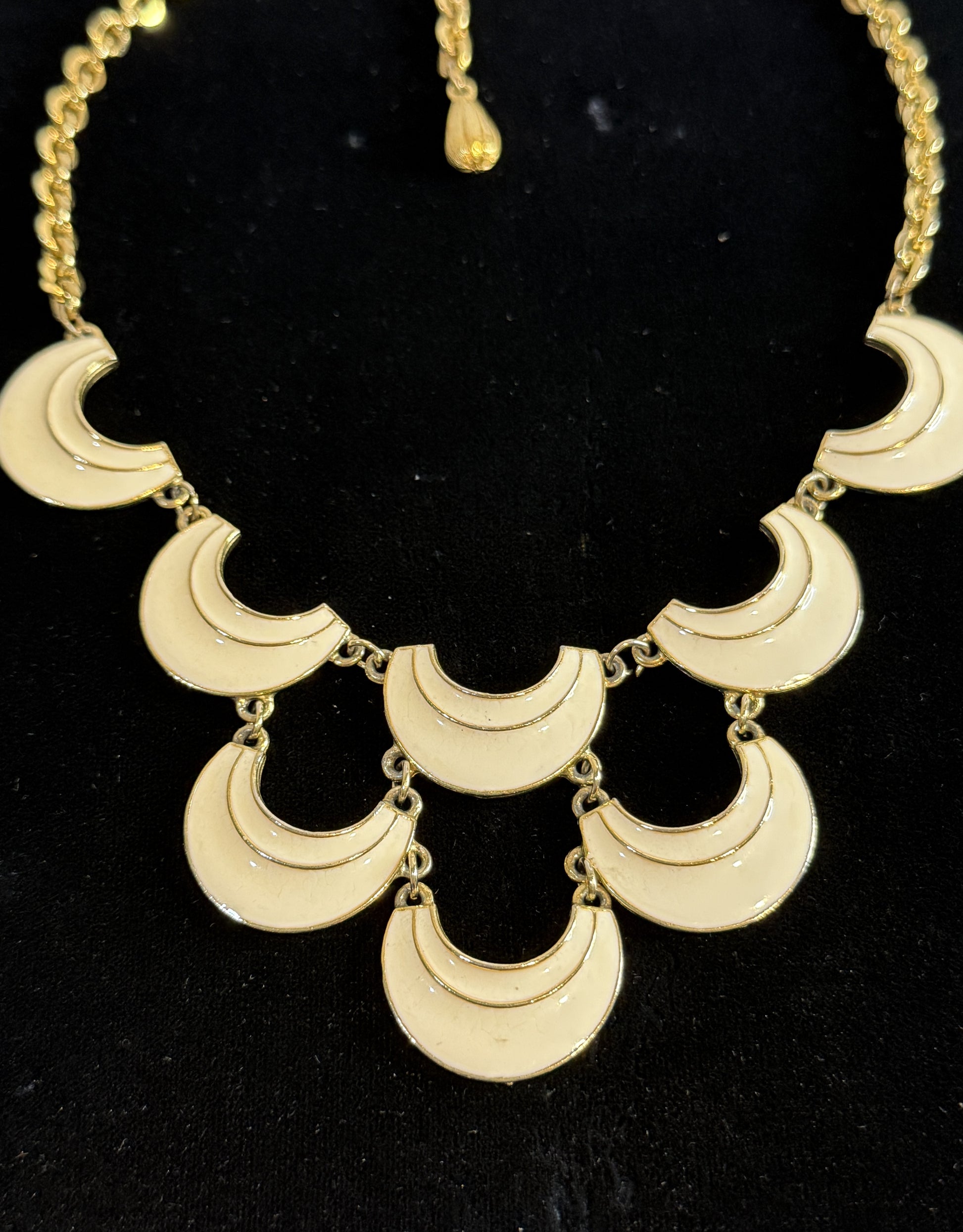 A gold signed Florenza statement necklace featuring multiple crescent moon-shaped links in cream enamel. 