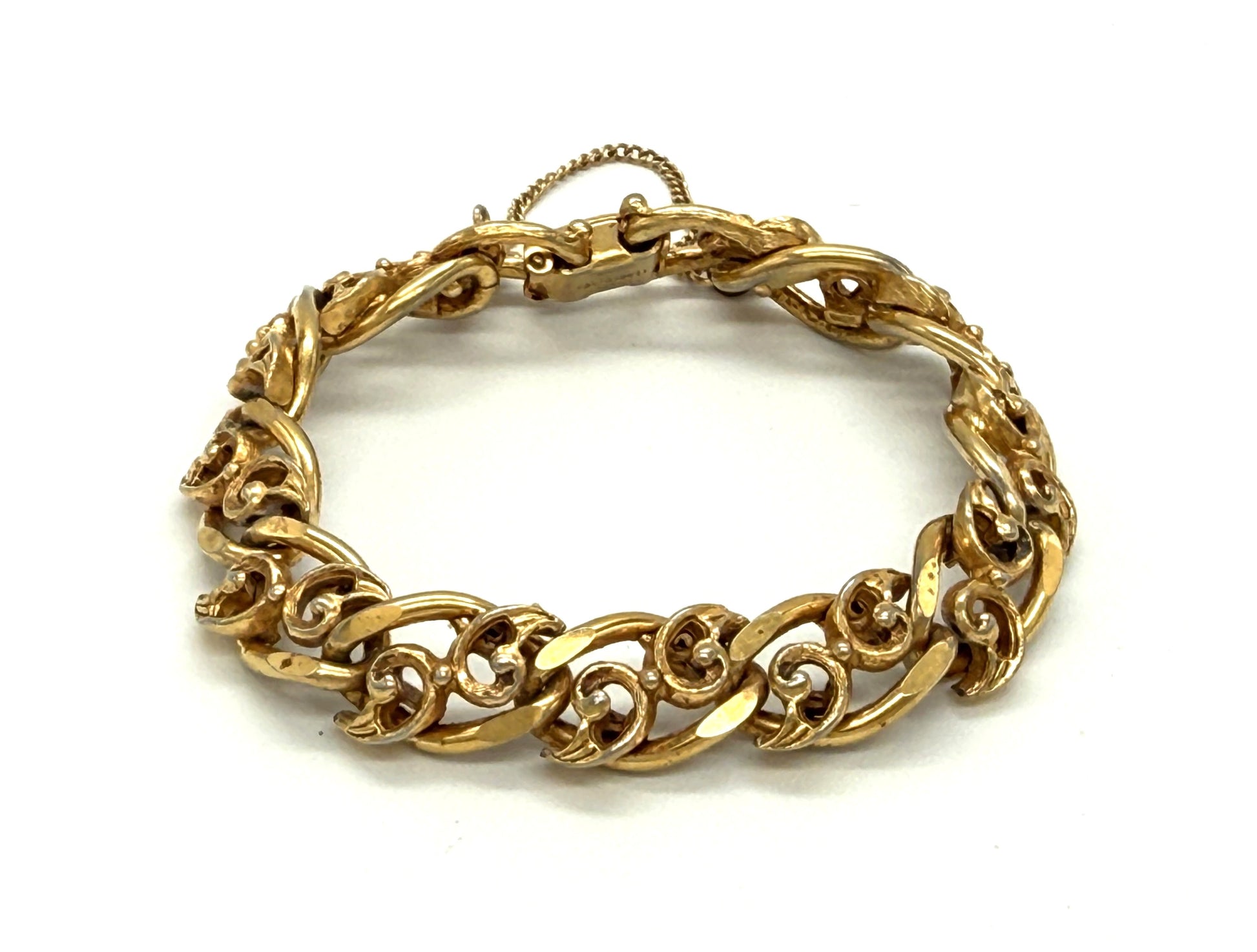 A gold-toned chunky chain bracelet with ornate, swirling links, vintage signed Florenza