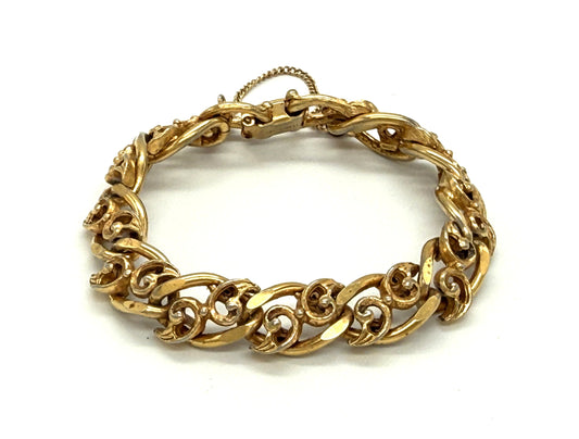 A gold-toned chunky chain bracelet with ornate, swirling links, vintage signed Florenza