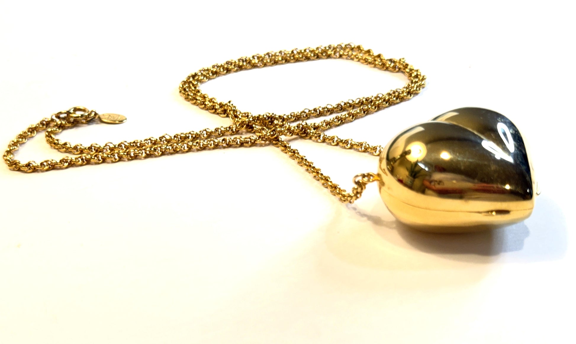 A gold heart-shaped locket pendant on a textured gold chain, signed Diane Von Furstenberg oversized puffy heart